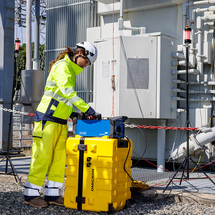 Field engineer using OMICRON CPX 200 for multifunctional testing at a power distribution site.