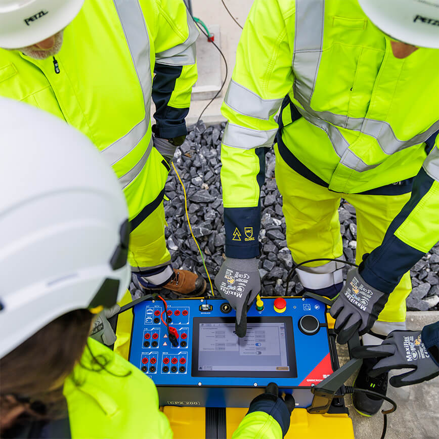 Team of technicians in safety gear collaborating around the CPX 200, looking at the touchscreen in an substation.