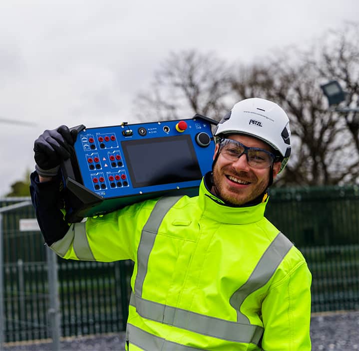 Engineer carrying the lightweight OMICRON CPX 200 testing device on shoulder and feels happy.